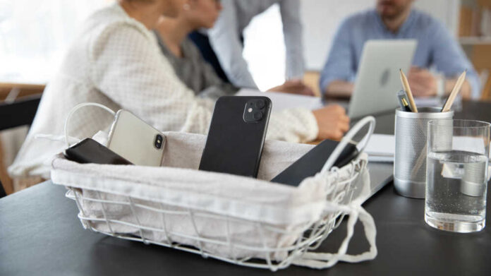 Close,Up,Of,Employee,Place,Smartphone,Gadgets,In,Basket,Attending