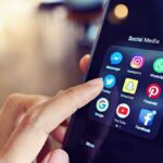 Finger tapping social media app icons on a smartphone.