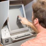 Person using touchscreen voting machine in polling booth.