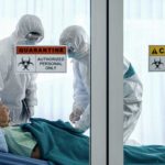 Healthcare workers in protective gear in quarantine room.