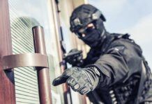 SWAT officer reaching for door handle.