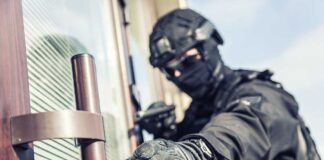 SWAT officer reaching for door handle.