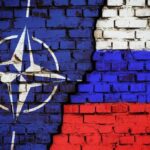 NATO logo and Russian flag painted on brick wall.