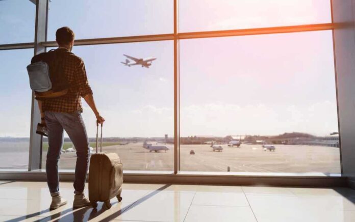 506777470 featured image Traveler with luggage watches airplane take off at airport.