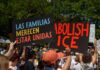 People holding protest signs outdoors against ICE policies