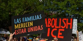 People holding protest signs outdoors against ICE policies