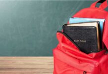 Red backpack with books on wooden table