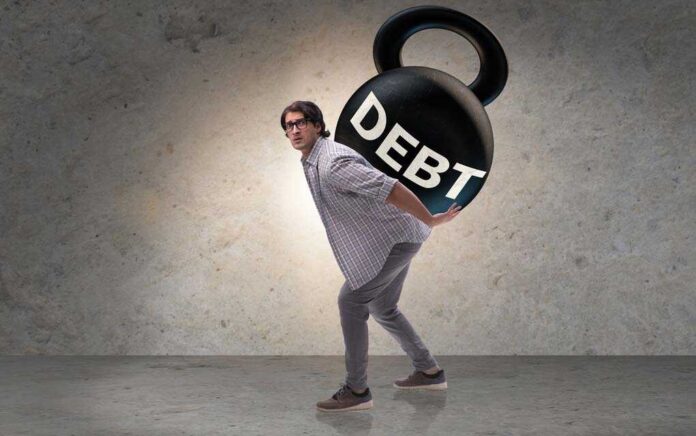 1334923313 featured image Person carrying large kettlebell labeled "DEBT".