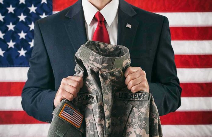 1444441475 featured image Man in suit holding military uniform American flag