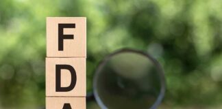Wooden blocks spelling FDA with magnifying glass nearby