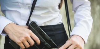 Person placing gun into a handbag.