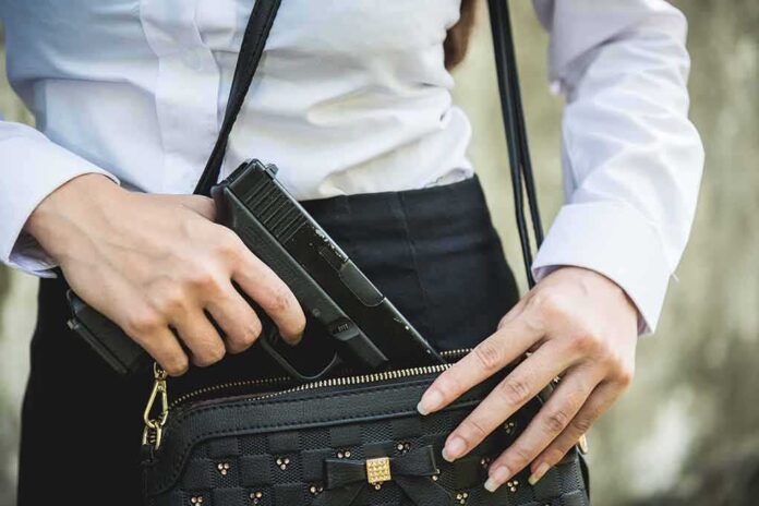 Person placing gun into a handbag.