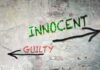 a stucco wall with the word inncent written in green paint, and the word guilty written in red paint