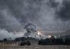 Explosion with smoke rising over rural landscape
