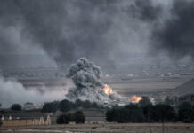 Explosion with smoke rising over rural landscape