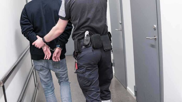 1082126789 featured image Officer escorting handcuffed person down hallway
