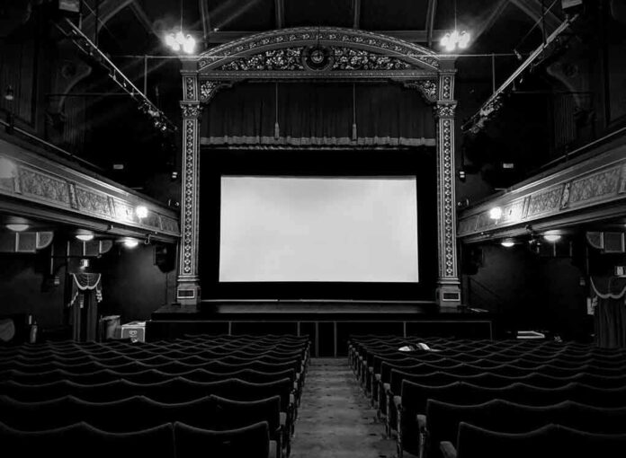 Empty theater with ornate decor and projection screen