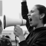 Person shouting into megaphone at protest rally