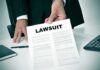 Person holding a document labeled Lawsuit
