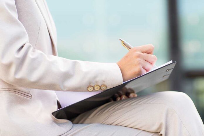 298063787 featured image Person in beige suit writing on a clipboard
