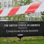 U.S. Embassy sign behind red-and-white caution tape