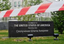 U.S. Embassy sign behind red-and-white caution tape