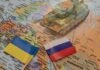 Toy tank on map with Ukraine and Russia flags