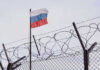 Flag above barbed wire fence