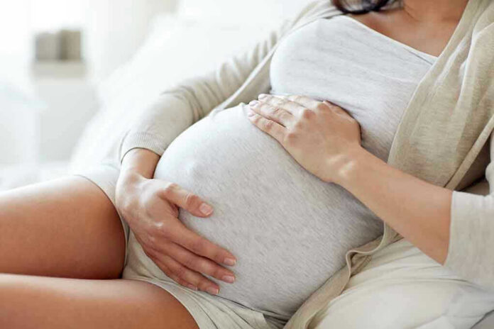 564114571 Pregnant woman holding her belly, sitting comfortably