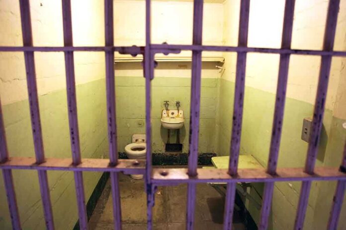 shutterstock_208632826.jpg Interior of a prison cell with a toilet, sink, and metal bars