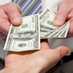 Two hands exchanging cash bills in a business context