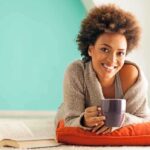 SHOCKING Coffee Transformation Nobody Saw Coming A woman lying on a cushion with a coffee cup, smiling at the camera