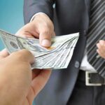 Senator EXPOSES $11 Billion Rigged Contract Scheme Two hands exchanging cash in a business setting