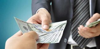 Two hands exchanging cash in a business setting