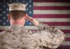 A soldier in uniform saluting in front of the American flag