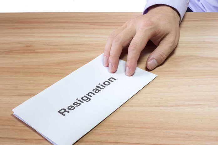 427496692 Hand holding a resignation letter on table.