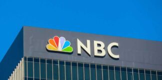NBC logo displayed on a building against a clear blue sky