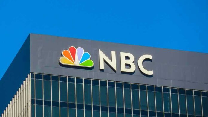 NBC logo displayed on a building against a clear blue sky