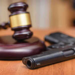 13-Year-Old MURDERS Friend Playing With Gun Gavel and handgun on a wooden surface.
