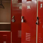 Predator Coach Cover-up Explodes in Texas Red lockers with padlocks, one open with hanger.
