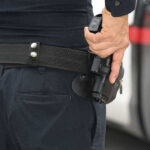 Staffer Killed—No One Saw The RAGE Coming Person holding a gun in a holster.