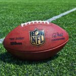 Head Coach Meltdown — Football World Stunned An NFL football resting on a green grass field