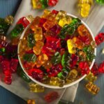 Halloween Horror — Dangerous FAKE Candy Is Circulating A bowl filled with colorful gummy bears surrounded by scattered candies