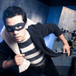 Rolex Heist Backfires—Robber Never Saw THIS Coming A masked thief in a striped shirt holding a bag while emerging from a bank vault
