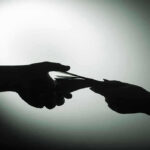 Cartel Bribes EXPLODE—MULTIPLE Sheriffs BUSTED Silhouette of hands exchanging money in dim light.