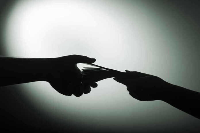1028993377 Silhouette of hands exchanging money in dim light.
