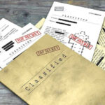 Classified documents with Top Secret stamps on wooden surface.