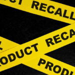 Yellow tape with product recall text on black background.