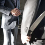 Two men shaking hands, one holding hidden knife.