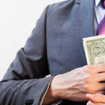 Congresswoman ARRESTED For Stealing Hurricane Money Person in suit putting dollars in jacket pocket.